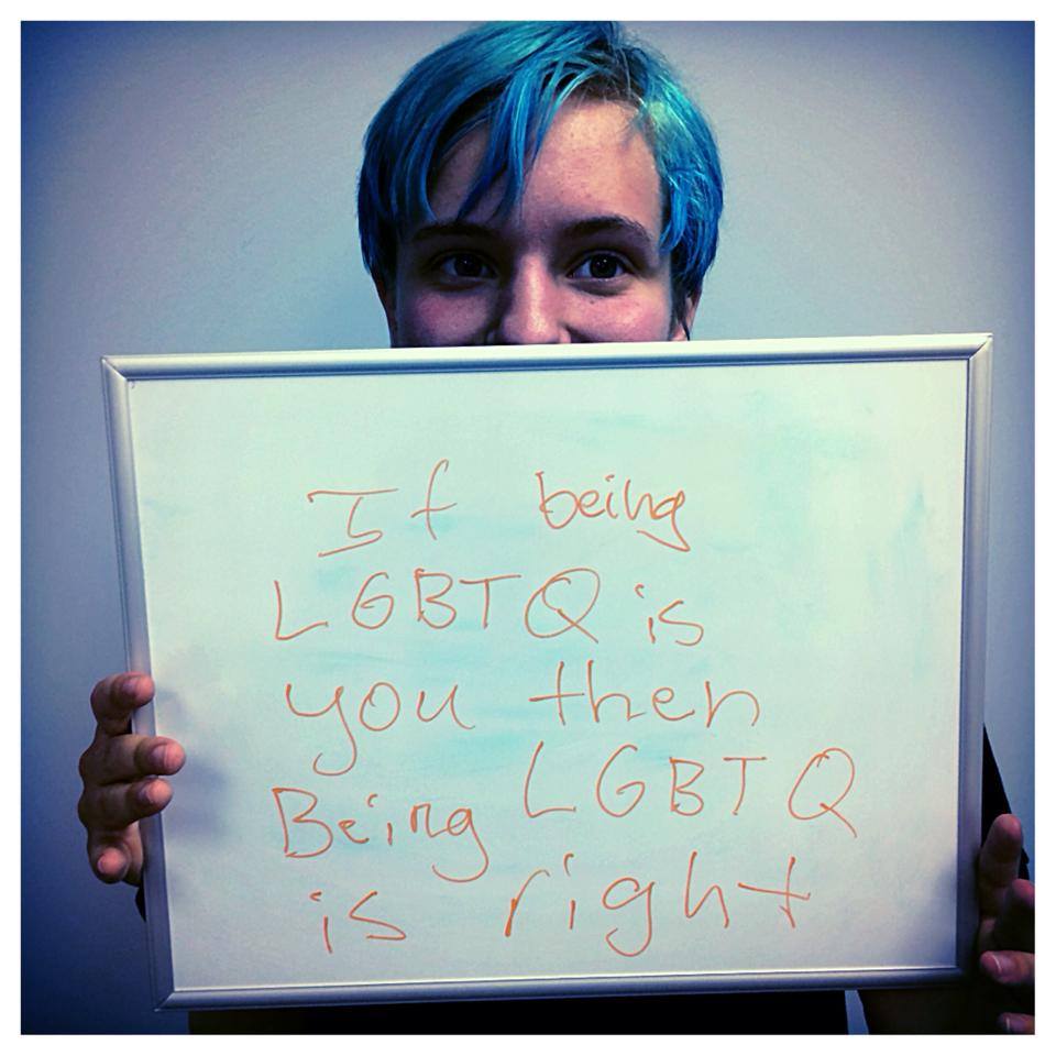 youth holding sign "if being LGTBQ is you then being LGBTQ is right"